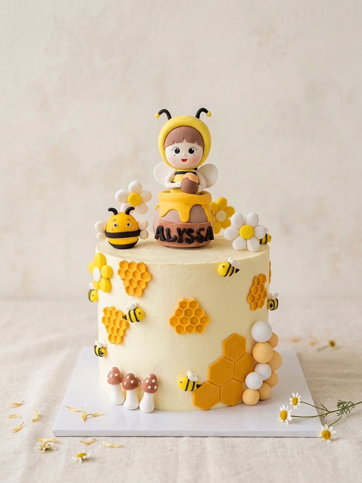 Bee-themed birthday cake with handmade characters, honeycomb and daisies