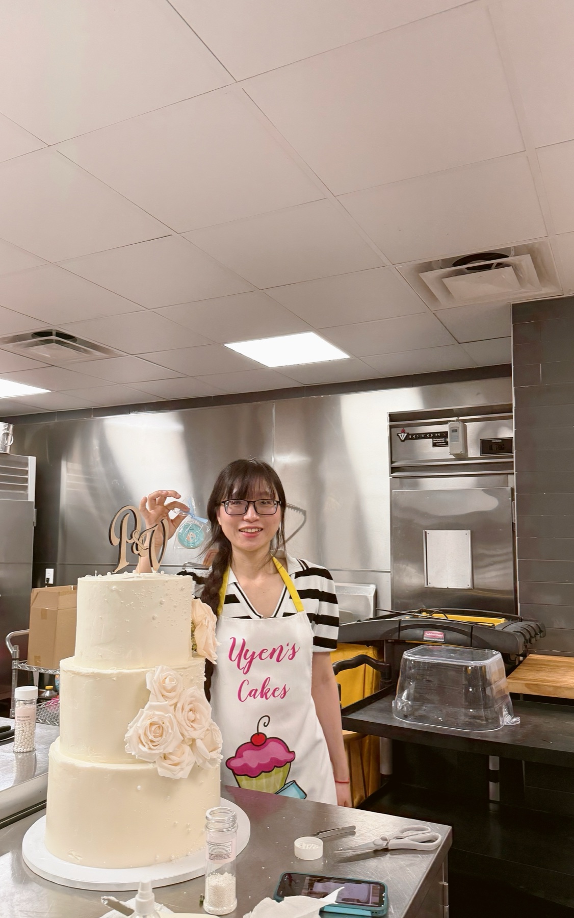 Uyen beside her three-tier white rose wedding cake